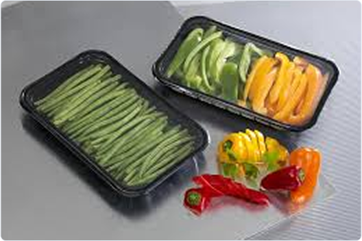 "Fresh cut vegetables in black vacuum-sealed plastic trays including green beans, bell peppers, and sliced capsicum"